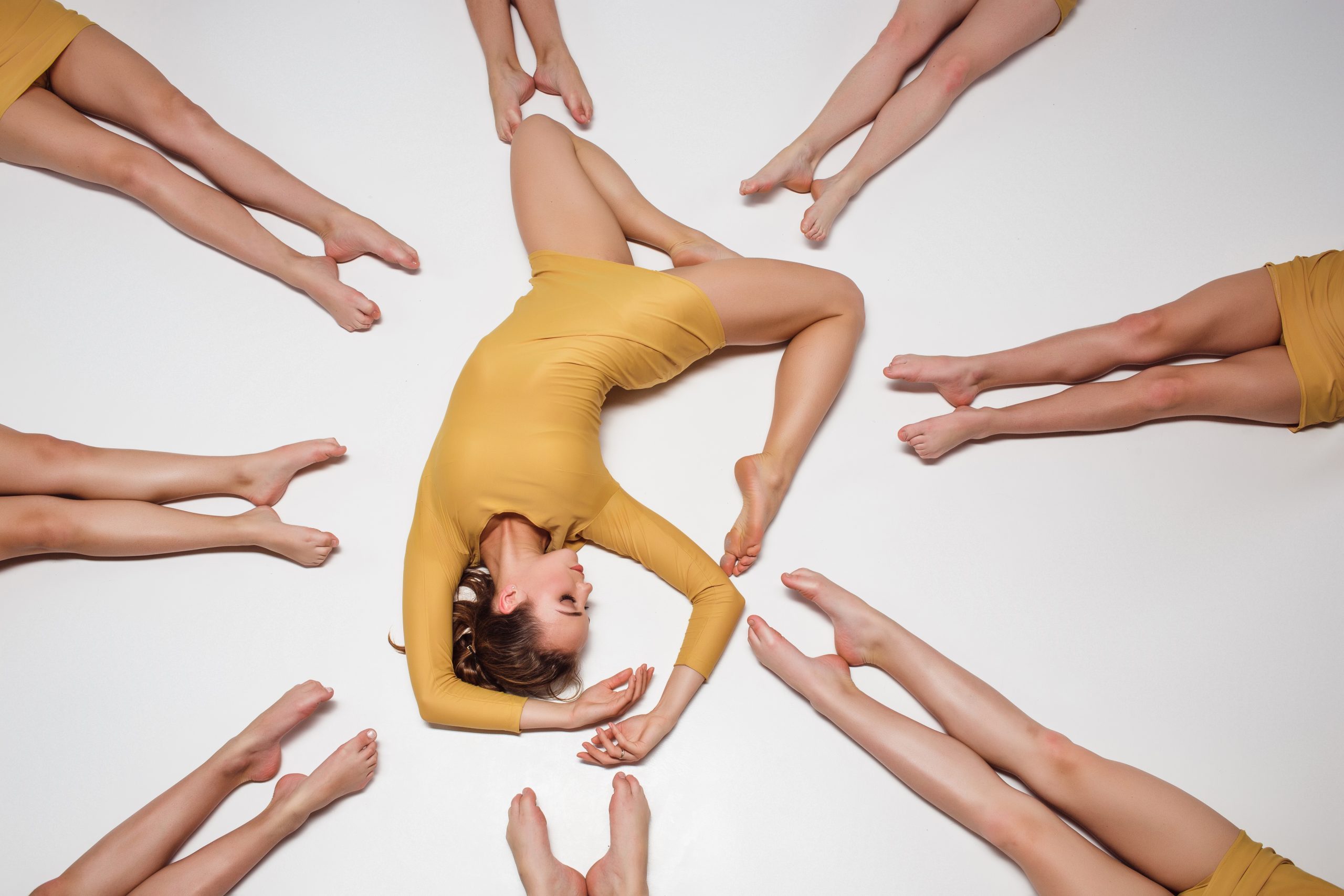 The group of modern ballet dancers lying on the floor and posing on gray background